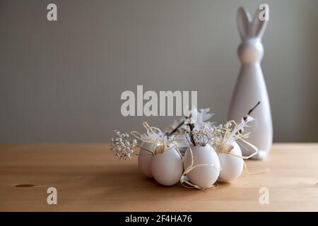Beautiful decoration idea for easter time, easter bunny made of porcelain with easter wreath made of white eggs. Stock Photo