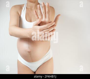 Pregnant woman feeling hand and wrist pain. Carpal tunnel syndrome. Female with finger, hand and wrist problems. Swollen hands during pregnancy Health Stock Photo