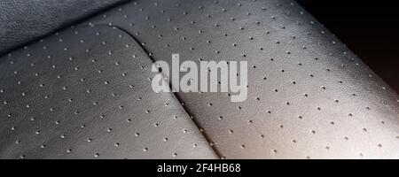 Close-up detail view of modern black perforated ventilated luxury car seat. Part of dark vehicle interior. Auto detailing and leather polish skin Stock Photo