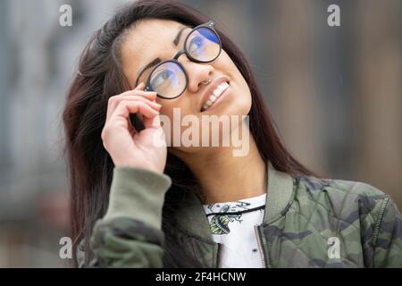 Charming concentrated Asian female using curler on eyelashes while doing makeup in front of mirror at home Stock Photo
