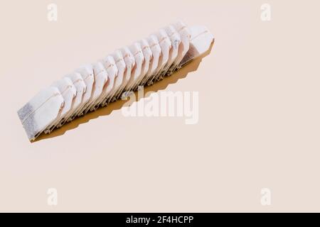From above of paper tea bags arranged in row on beige background with empty space Stock Photo