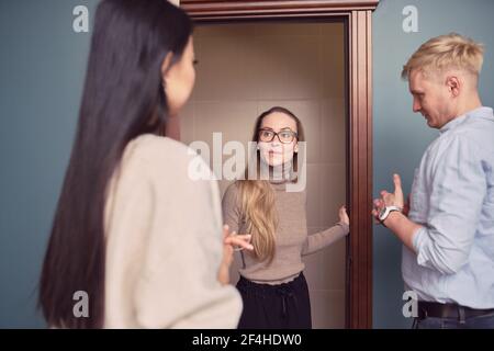 Female psychologist standing in doorway of office during appointment with couple having problems in relationship Stock Photo