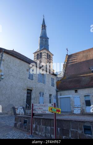 St Pourcain Sur Sioule, France - August 22, 2019: Bell tower of the Sainte Croix church and Houses surrounding the Benedictine courtyard in Saint-Pour