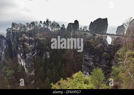 Panorama view of Bastei Bridge and sandstone mountains in Saxon Switzerland National Park on a foggy winter day, Saxony, Germany Stock Photo