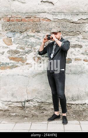 Young hipster man taking a photo with an old, retro camera. Copy space Stock Photo