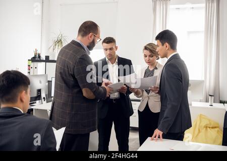 Young promising employees of an international it company communicate and share financial news during a break Stock Photo