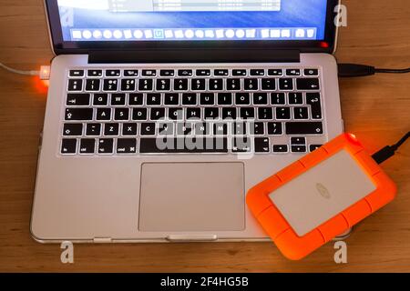 Laptop computer with a LACie rugged external hard drive attached. Backing up data. Stock Photo