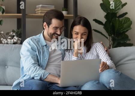 Close up happy laughing young couple watching video, using laptop Stock Photo