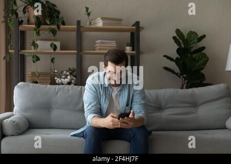 Smiling man wearing glasses having fun with phone at home Stock Photo