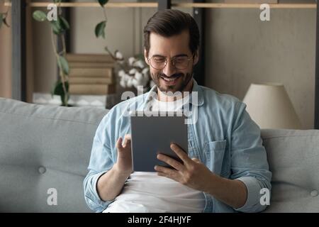 Close up smiling man wearing glasses using tablet at home Stock Photo