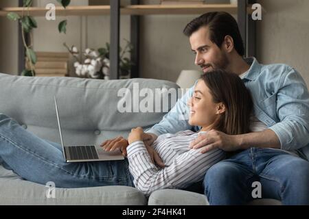 Side view smiling woman using laptop, lying on boyfriend laps Stock Photo