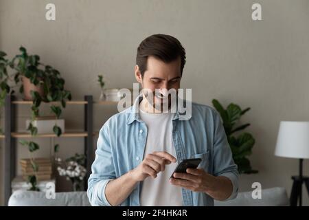 Close up smiling man using phone, browsing apps, having fun Stock Photo