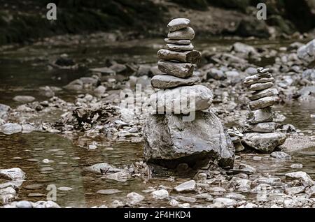 Two piles of stacked rocks, balancing in a riverbed. Rocks laid flat upon each other to great height. Balanced rock piles at the creek. Stock Photo