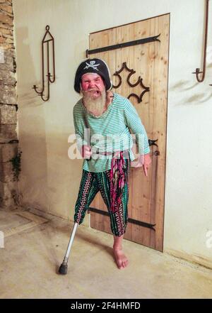 Older bearded man missing lower right leg using his disability to dress up as a pirate. Stock Photo