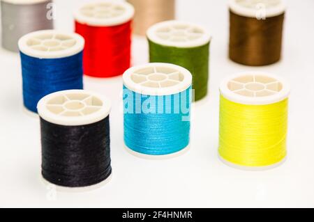 A closeup of various colorful sewing threads on the white surface Stock Photo