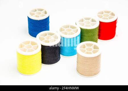 A closeup of various colorful sewing threads on the white surface Stock Photo