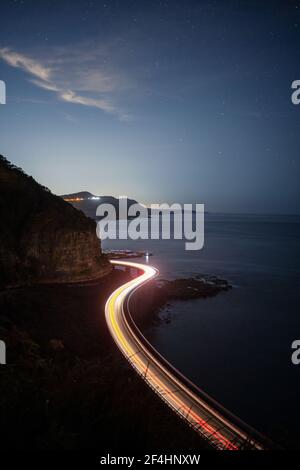 Long exposure light trail of sea cliff bridge with sparkling stars in the sky Stock Photo