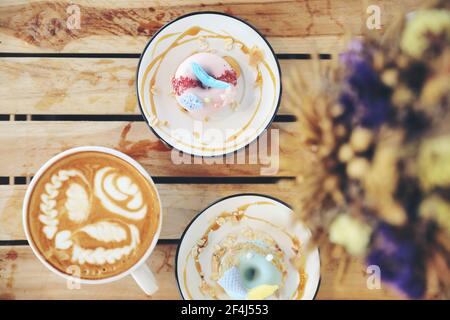Fancy donut with cute mermaid on top with cappuccino coffee on wood background Stock Photo