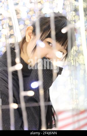 Young pretty girl wearing black cotton sweatshirt on bokeh background at night Stock Photo