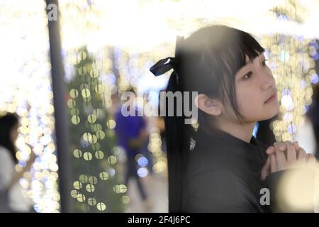 Young pretty girl wearing black cotton sweatshirt on bokeh background at night Stock Photo