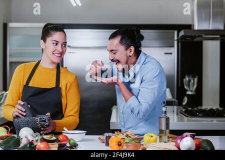 latin couple cooking mexican sauce together in their kitchen at home in Mexico city Stock Photo