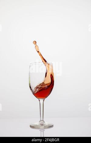 Splash of red wine in glass on white background. Stock Photo