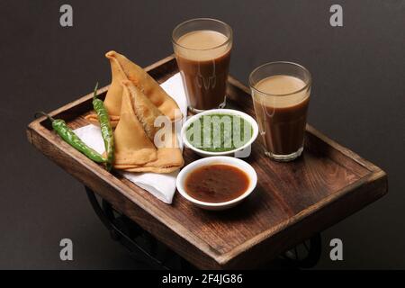 Indian snack Homemade spicy and delicious samosa served with green, tamarind chutney cutting masala tea, chai, Stock Photo