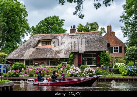 Giethoorn, Netherlands - July 6, 2019: Tourists on a motorboat navigating the canals of Giethoorn, also known as the Venice of Netherlands Stock Photo