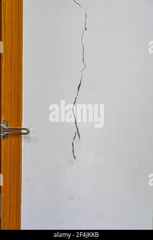 Vertical photo of cracked wall texture next to the door Stock Photo