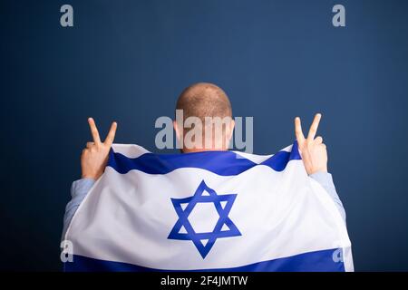 Israeli patriot holding the flag of Israel on his shoulders Stock Photo