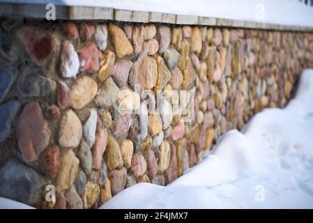 Wall decorated with multi-colored decorative stone. Down below the snow Stock Photo