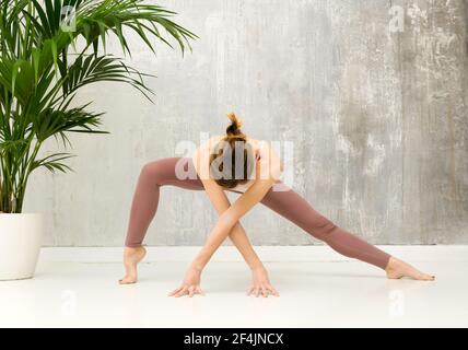 Fit healthy woman doing a Parighasana variation yoga pose with wide leg stretch to strengthen her hip flexors and quads in a healthy active lifestyle Stock Photo