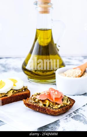 Toasted breads with poached eggs, avocado and salmon. Guacamole sandwiches. Healthy breakfast. Olive oil. Sesame seeds. Vegetarian healthy eating. Die Stock Photo