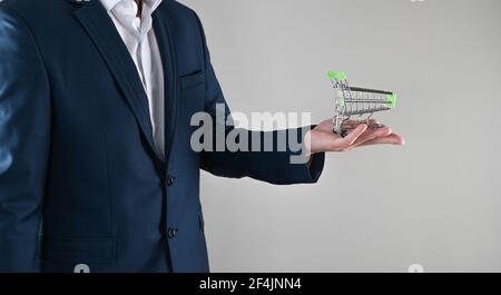 a man in a suit holds a shopping cart in his hands. High quality photo Stock Photo