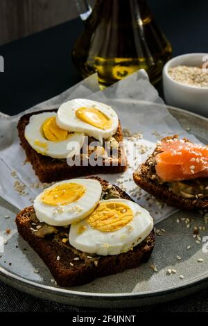 Toasted breads with poached eggs, avocado and salmon. Guacamole sandwiches. Healthy breakfast. Olive oil. Sesame seeds. Vegetarian healthy eating. Die Stock Photo