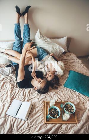 Caucasian couple are sitting in bed upside down making a selfie before eating cereals with milk Stock Photo
