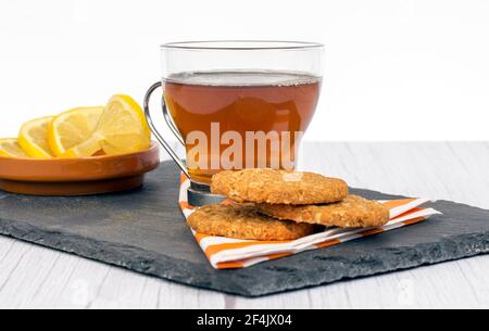 Oatmeal cookies and tea with lemon on a tray on white background, healthy and natural food for people who take care of their diet Stock Photo
