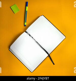 Open notebook with pen and stickers on orange background. Notebook for writing thoughts and notes. Weekly calendar for making plans for day or week. Stock Photo