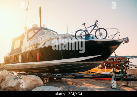 Boat cabin motorboat cruiser yacht on shore ready for maintenance and transportation. Stock Photo
