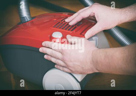 Red vacuum cleaner is opened by male hands for close-up inspection Stock Photo