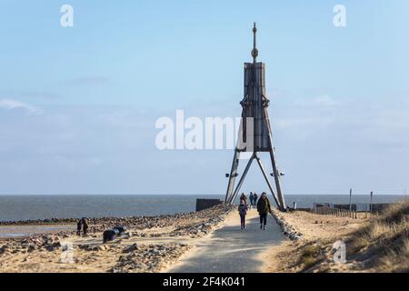 Cuxhaven, Germany - March 14, 2021: Day-trippers visiting Kugelbake beacon, landmark of the city on Elbe river estuary. View along the footpath on the Stock Photo