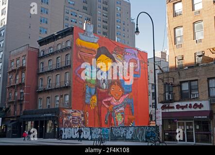 Murals by the twin brothers Otavio and Gustavo Pandolfo, street artists who call themselves Os Gemeos, flank a vacant lot on 14th Street in Manhattan. Stock Photo