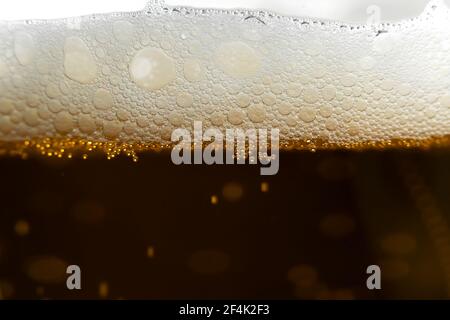 Close-up of a glass of beer with bubbles and foam on a dark background, macro. Background beer Stock Photo