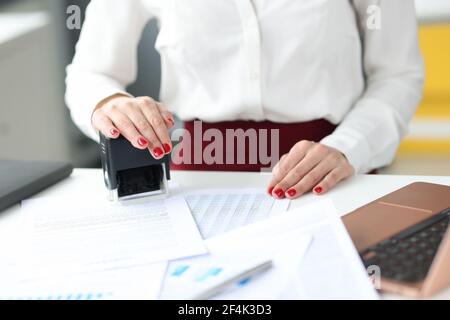 Businesswoman puts stamp on documents on work table Stock Photo