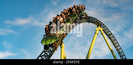 People screaming and holding up hands during roller coaster ride