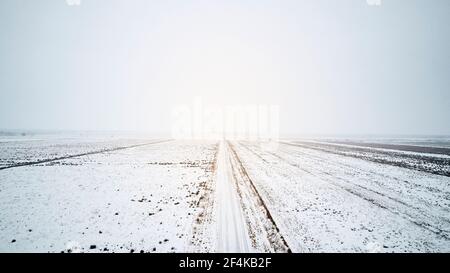 a foggy white snowy empty road in winter Stock Photo
