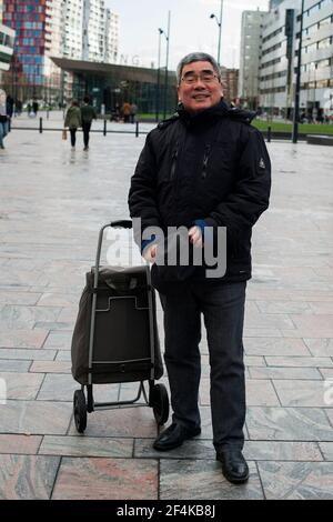 Rotterdam, Netherlands. Middle aged Chinese man with luggage entering Grand Central Station. Stock Photo