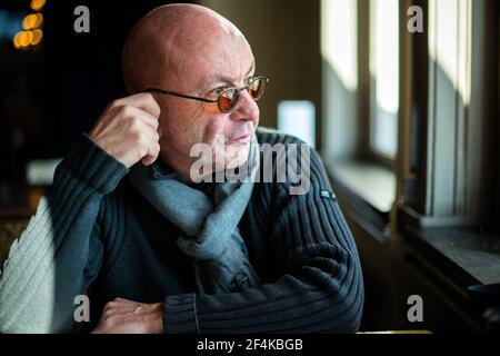 Rotterdam, Netherlands. Middle aged balding man overlooking the river from his restaurant lunch table, while dealing with a depression. Stock Photo