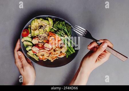 Woman eating buddha bowl with quinoa, shrimps and tahini dresssing Stock Photo