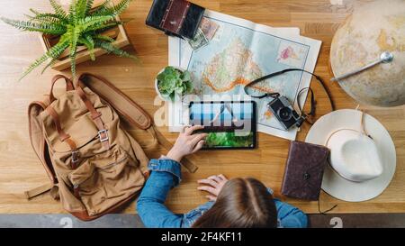 Top view of young woman with maps planning vacation trip holiday, desktop travel concept. Stock Photo